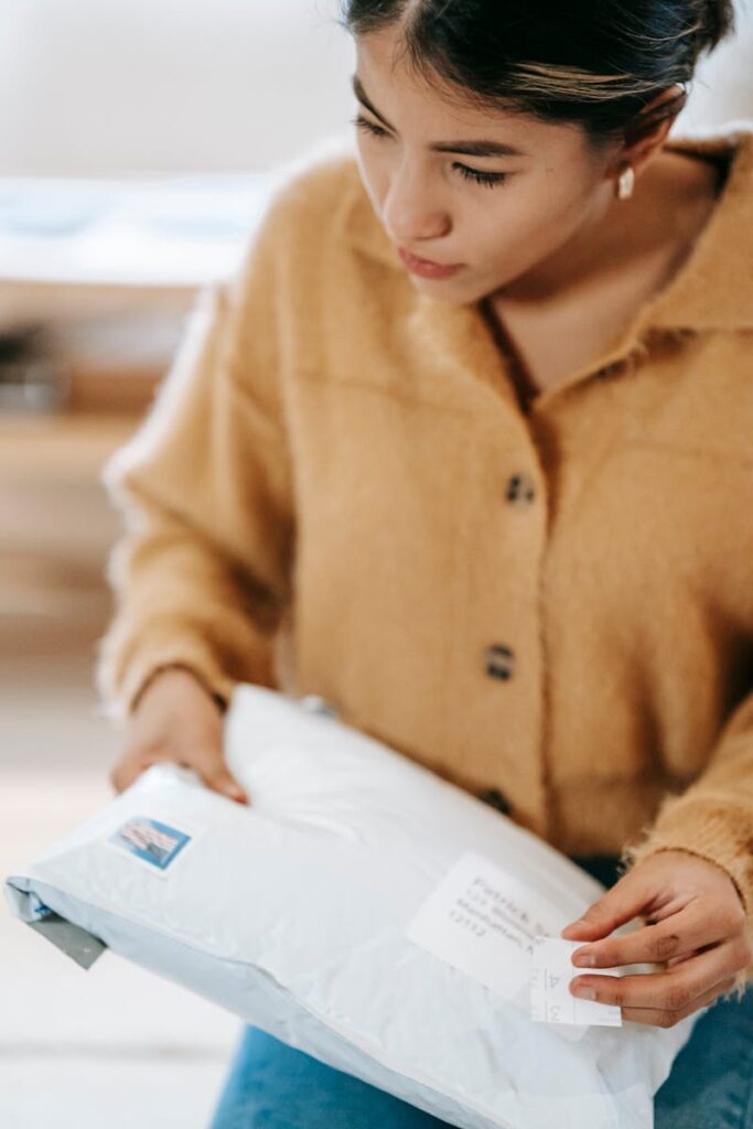 A woman in a cardigan carefully examines a mail parcel, highlighting home delivery.